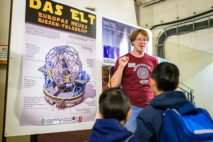 Wissenschafter steht vor einem Poster und erklärt das (European Large Telescope) ELT